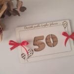 Handmade papierová biela karta s číslom 50, ručne viazané červené mašle.
